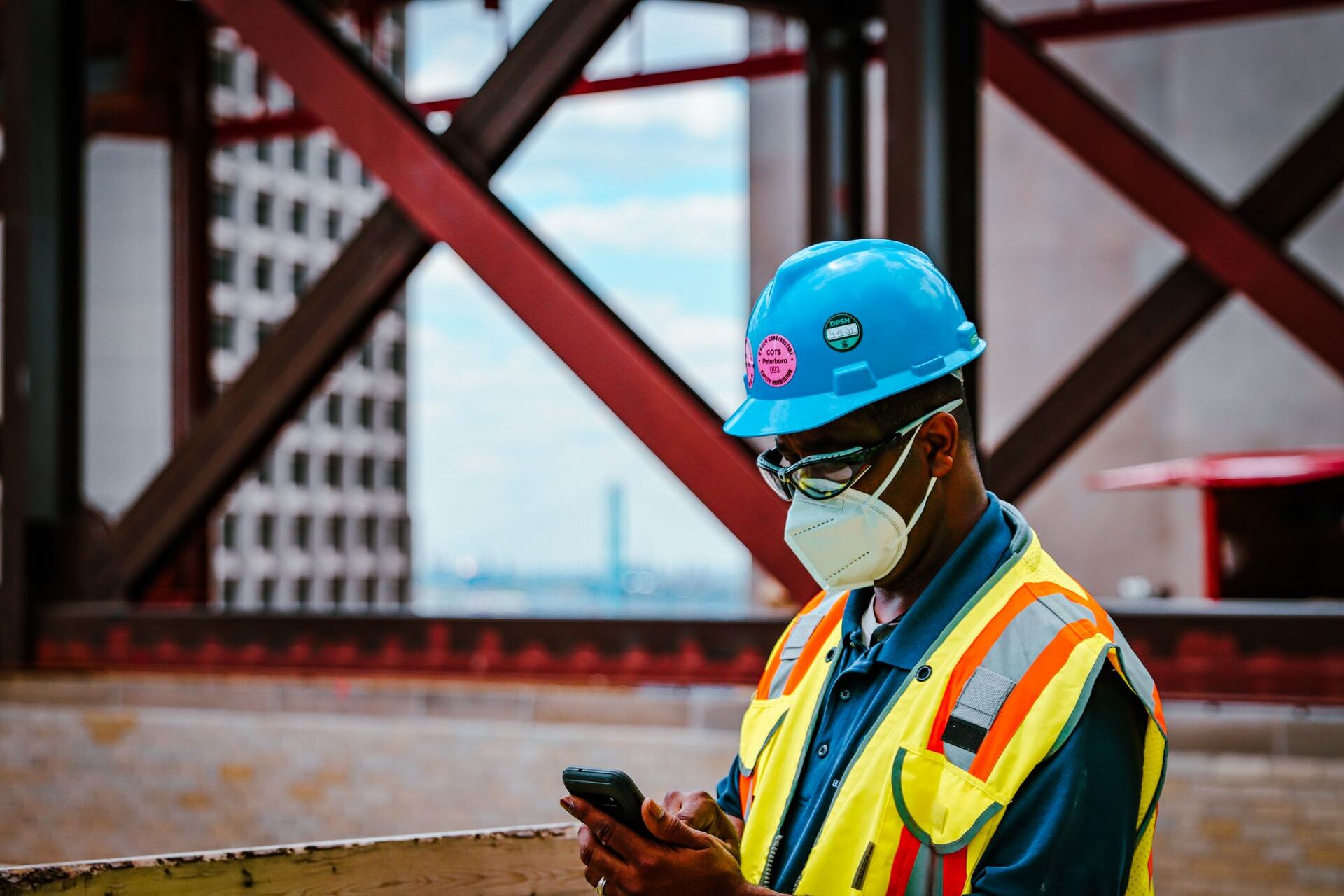 A tradesperson in hi-vis checking their phone on a construction site
