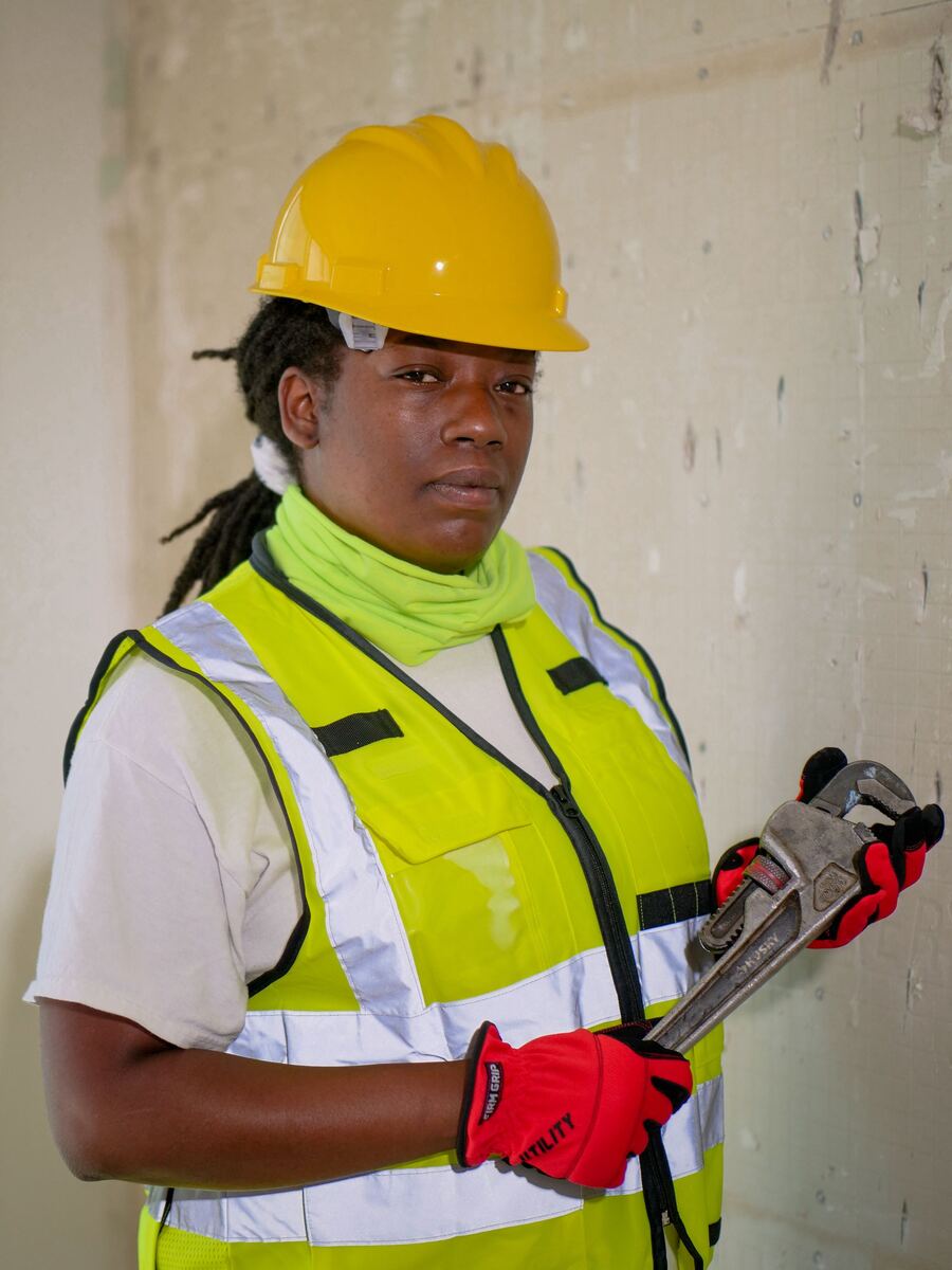 A plumber in hi-vis holding a pipe wrench